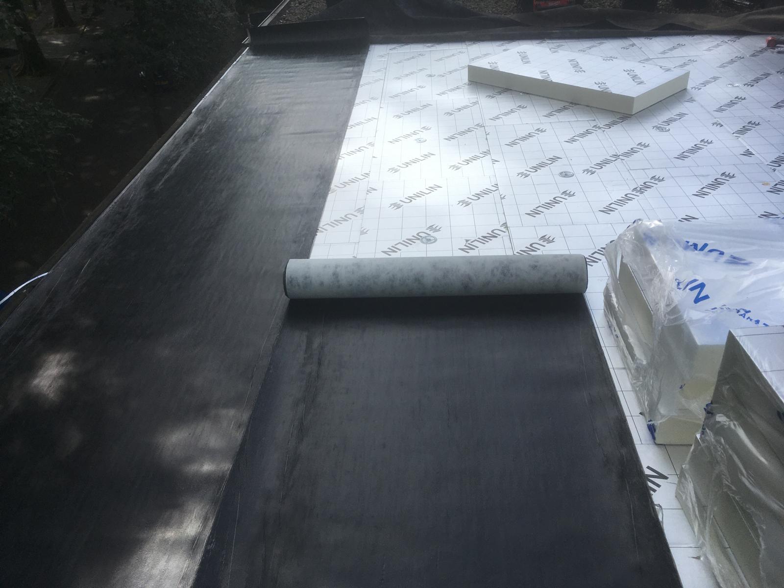 Tijdens: het uitleggen van de bitumen onderlaag over de isolatieplaten